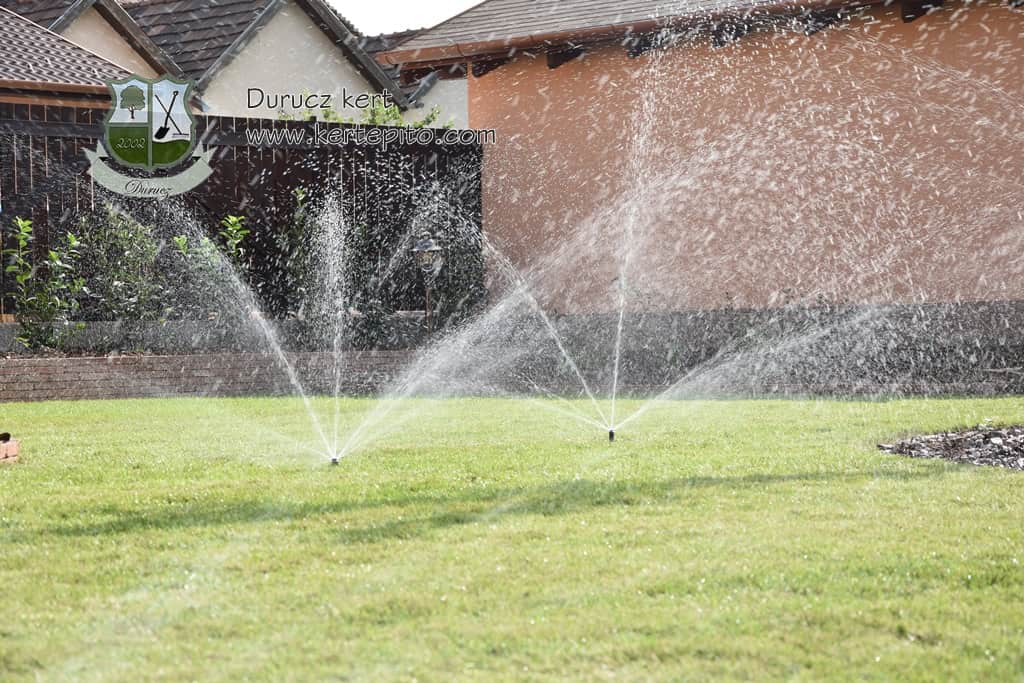 Öntözőrendszer a gyep öntözéséhez, friss vízpermet a zöld területen.