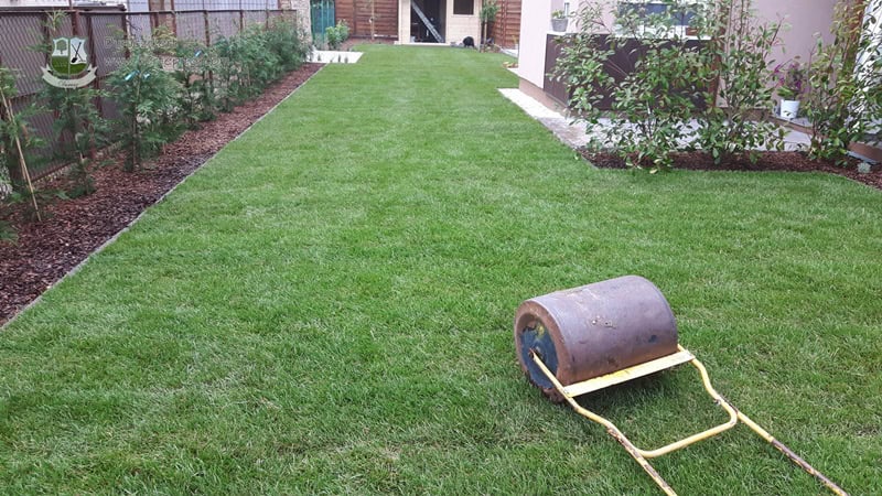 Fűnyíró a zöld gyepen, kertépítési munkák folyamatban.