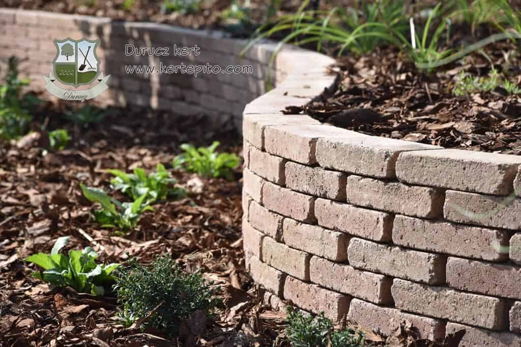 Ágyás téglából, frissen ültetett növényekkel a kertben.