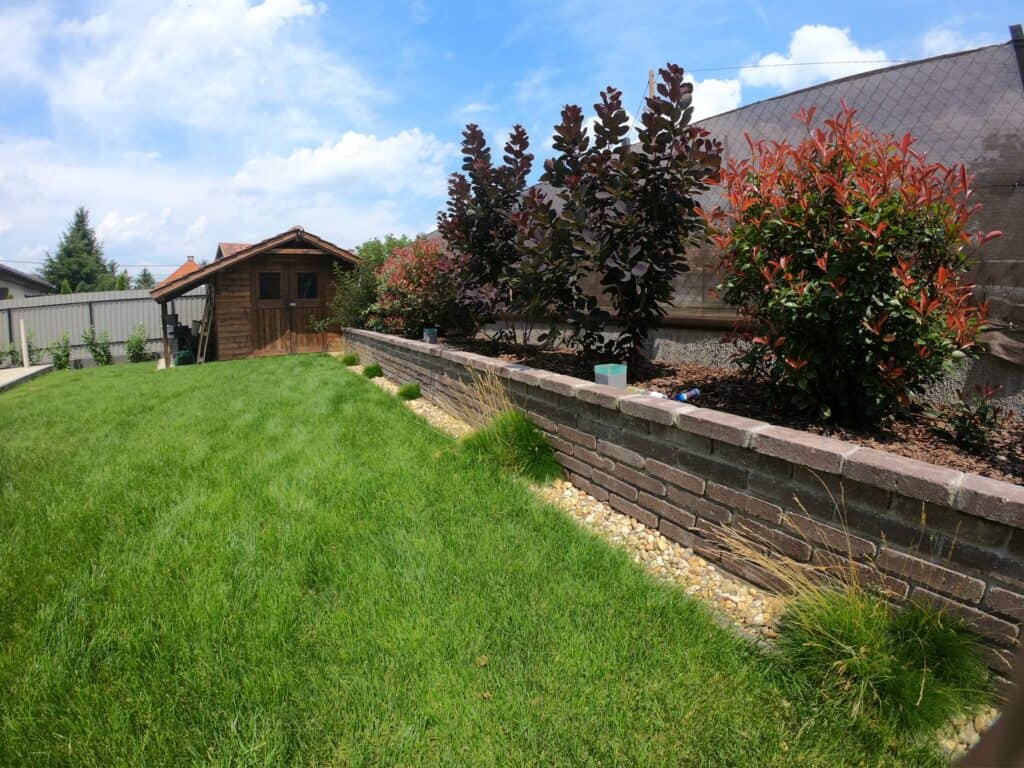 Színes növények és bokrok magaságyásban, jól karbantartott kert.