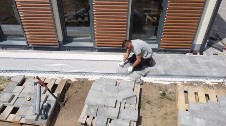 Férfi szakember helyezi el a gyorsszegélyt a kertben, a modern kertépítés részeként.